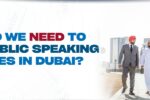 Three diverse professionals, dressed in formal attire, walk together in an urban setting with the Dubai skyline in the background. The bold text on the left reads, "Why do we need to learn public speaking courses in Dubai?" accompanied by Zabeel International Institute’s logo and website link, highlighting the importance of public speaking skills for professionals in Dubai.