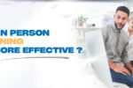 A cheerful group of professionals interacting around a computer screen in a bright office, with the text 'Online vs In Person Excel Training – Which is More Effective?' displayed next to the Zabeel International logo and website URL.